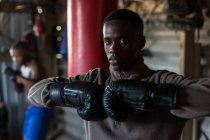 Retrato de boxeador masculino de pie con guantes de boxeo en el gimnasio - foto de stock