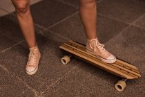 Низька секція жіночого фігуриста, що стоїть на скейтборді — стокове фото