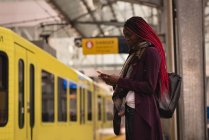 Donna elegante utilizzando il telefono cellulare alla piattaforma ferroviaria — Foto stock