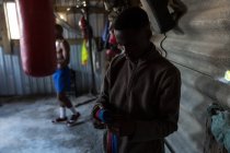 Мужчина боксер, завязывающий ручную упаковку на руках в фитнес-студии — стоковое фото