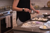Женщина готовит пирожки на кухне дома — стоковое фото
