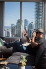 Hombre usando auriculares de realidad virtual en la sala de estar en casa - foto de stock