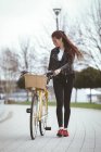 Красива жінка з велосипедом, що йде на тротуарі — стокове фото