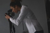Жіночий фотограф, який натискає фотографії з цифровою камерою у фотостудії — стокове фото