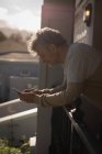 Uomo anziano utilizzando il telefono cellulare in veranda a casa — Foto stock