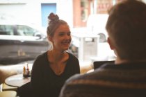 Усміхнена жінка розмовляє з чоловіком у кафе — стокове фото
