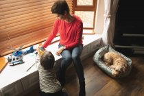 Mãe brincando com filho no peitoril da janela na sala de estar em casa — Fotografia de Stock