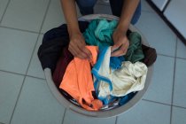 Крупный план женщины сортирует одежду в корзине для белья — стоковое фото