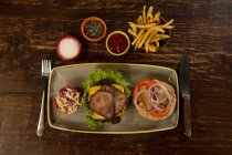 Burger de viande avec frites servi sur table en bois — Photo de stock