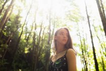 Beautiful woman standing in green forest on a sunny day — Stock Photo