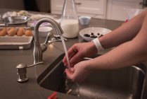 Mulher lavando as mãos na cozinha em casa — Fotografia de Stock