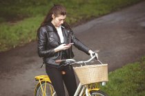 Beautiful woman on bicycle using mobile phone — Stock Photo
