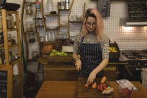 Молода жінка ріже овочі на рубаній дошці — стокове фото