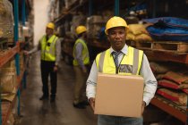 Portrait of male Staff holding cardboard box in warehouse — Stock Photo