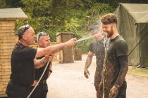 Treinador de lavagem de homens rosto com água no acampamento — Fotografia de Stock