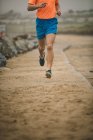 Low section of man jogging on boardwalk at beach — Stock Photo
