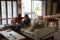 Casal de lésbicas usando tablet digital na sala de estar em casa — Fotografia de Stock
