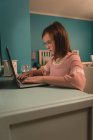 Chica usando el ordenador portátil en el dormitorio en casa - foto de stock