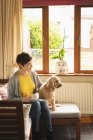 Mulher com cão tomando café na sala de estar em casa — Fotografia de Stock