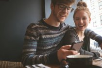 Glückliches Paar mit Handy im Café — Stockfoto