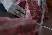 Primer plano del carnicero que tiene carne en la carnicería - foto de stock