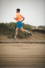 Young man jogging on boardwalk at beach — Stock Photo