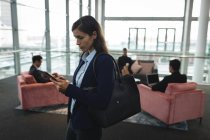 Концентрована бізнес-леді, використовуючи свій мобільний телефон в офісі — стокове фото