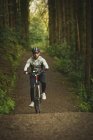 Ciclista em sportswear andar de bicicleta através da floresta exuberante — Fotografia de Stock