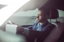Smart businessman driving a car — Stock Photo