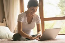 Frau benutzt Laptop auf Bett im Schlafzimmer zu Hause — Stockfoto