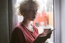 Портрет молодої жінки, що використовує мобільний телефон вдома — стокове фото