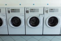 Quattro lavatrici di fila nella lavanderia — Foto stock
