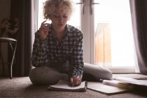 Junge Frau schreibt zu Hause auf Notizblock — Stockfoto