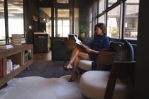 Empresária sentada no sofá e lendo documento no escritório — Fotografia de Stock