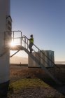 Engenheiro subindo as escadas de um moinho de vento em um parque eólico — Fotografia de Stock