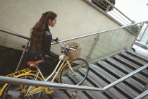 Beautiful woman with bicycle climbing up the stairs — Stock Photo