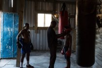Trainer unterstützt Boxer beim Tragen von Kopfbedeckungen im Fitnessstudio — Stockfoto