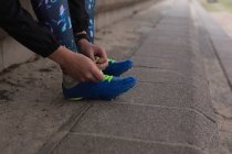 Жінка-спортсменка зав'язує шнурки на спортивному майданчику — стокове фото