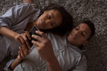 Casal usando telefone celular no quarto em casa — Fotografia de Stock