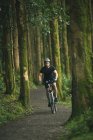 Cycliste en vêtements de sport équitation vélo à travers la forêt luxuriante — Photo de stock