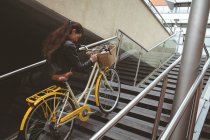 Bella donna con bicicletta salire le scale — Foto stock