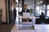 Бізнесмен стоїть і використовує ноутбук в офісі — стокове фото