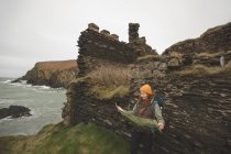 Женщина-туристка опирается на скалу и читает карту — стоковое фото