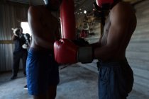Treinador assistindo jovem boxeador masculino no estúdio de fitness — Fotografia de Stock