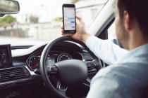 Бізнесмен, використовуючи мобільний телефон в сучасному автомобілі — стокове фото