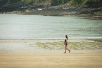 Belle femme marchant sur la plage par une journée ensoleillée — Photo de stock