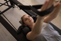 Mujer haciendo ejercicio en la máquina de estiramiento en el gimnasio - foto de stock