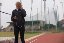 Жінка-спортсменка слухає музику на мобільному телефоні на біговій доріжці — стокове фото