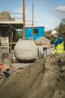 Інженер змішування цементу в бетономішалці на будівельному майданчику — стокове фото