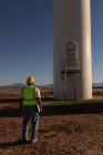 Инженер смотрит на ветряную мельницу на ветряной электростанции — стоковое фото